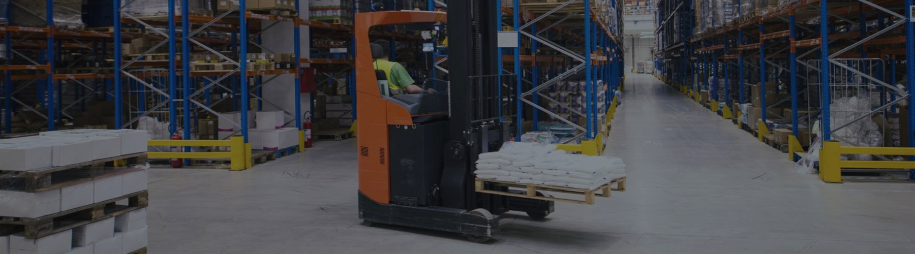 Forklift operating across a warehouse concrete traffic aisle